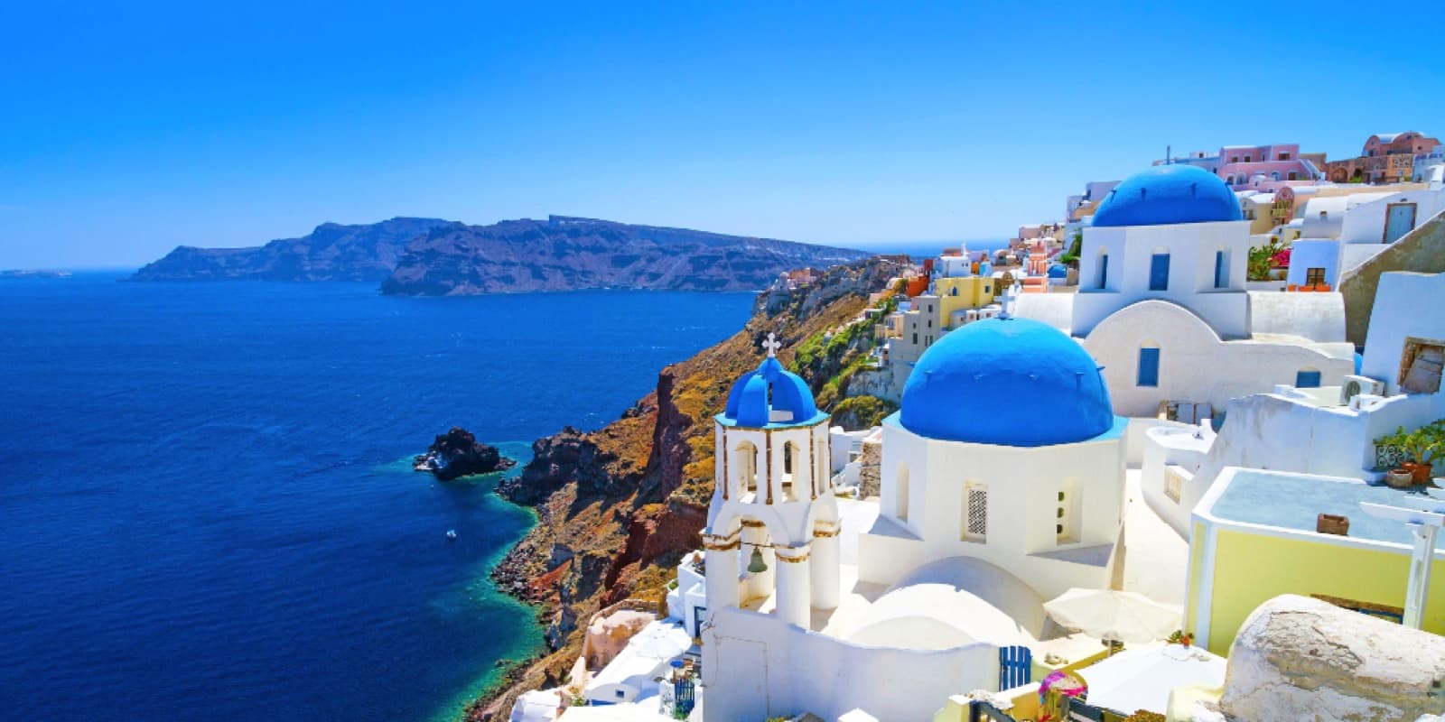White Cycladic buildings and blue domes overlooking the sea