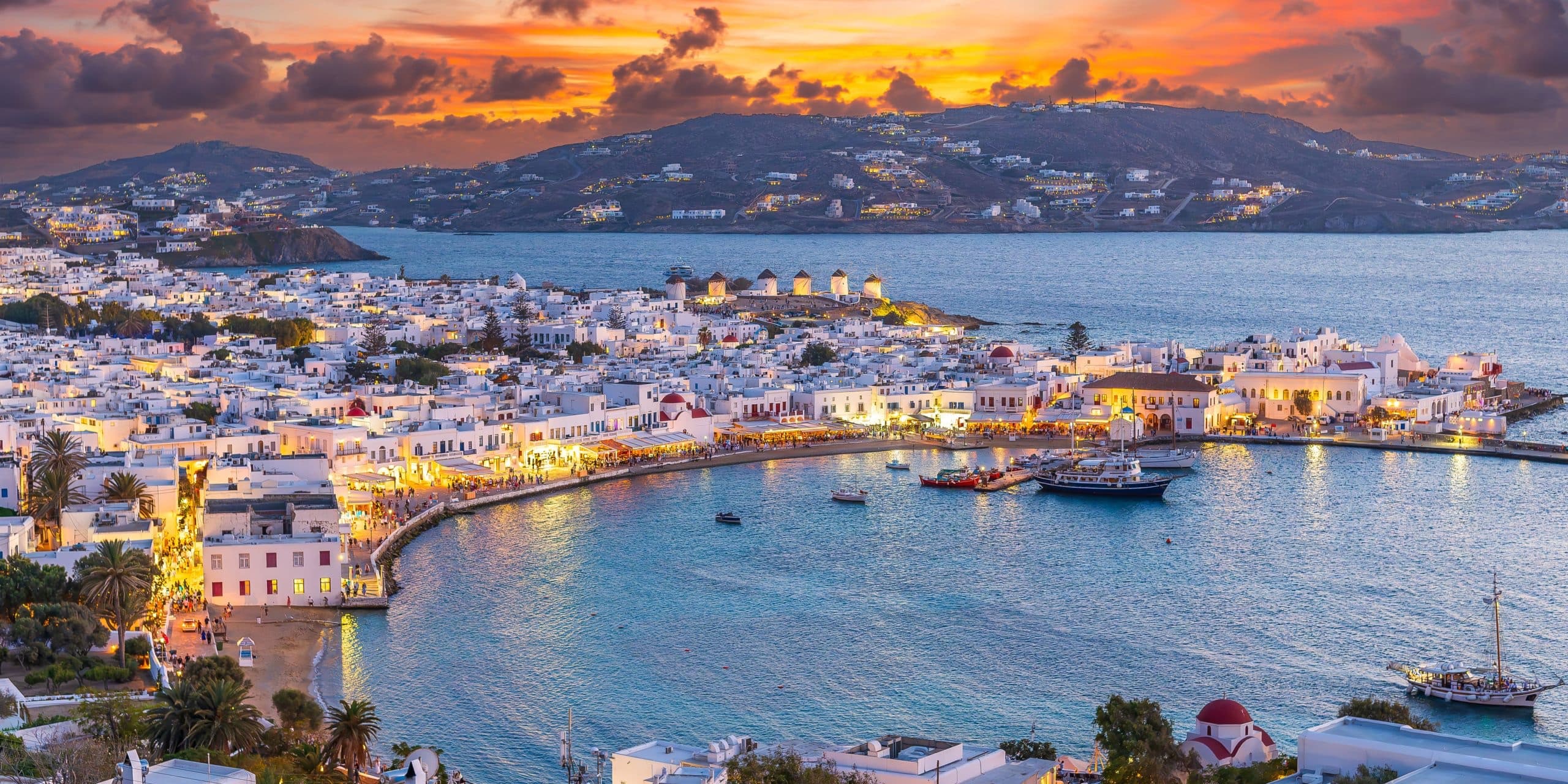 Mykonos town and harbor glowing at sunset over the Aegean Sea